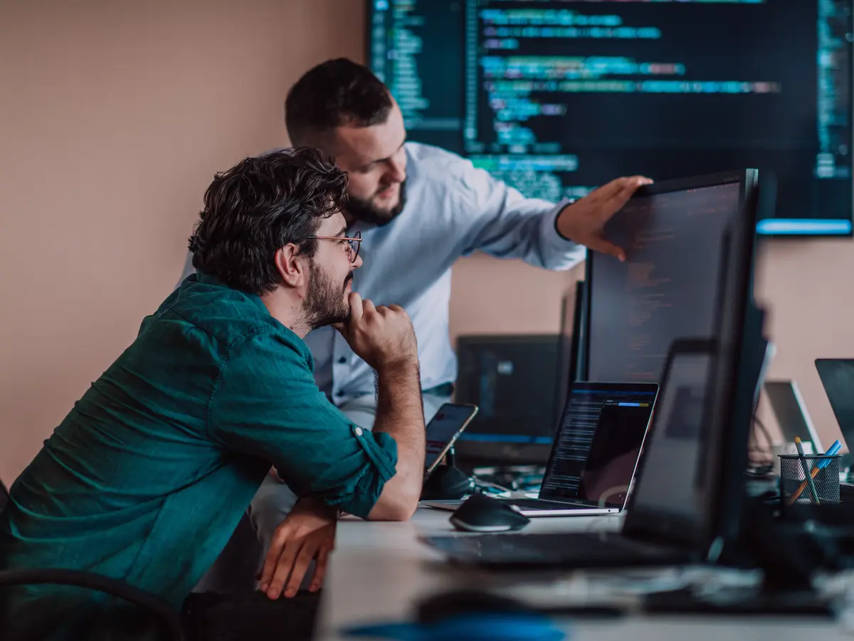 Zwei Entwickler besprechen Code an einem großen Monitor